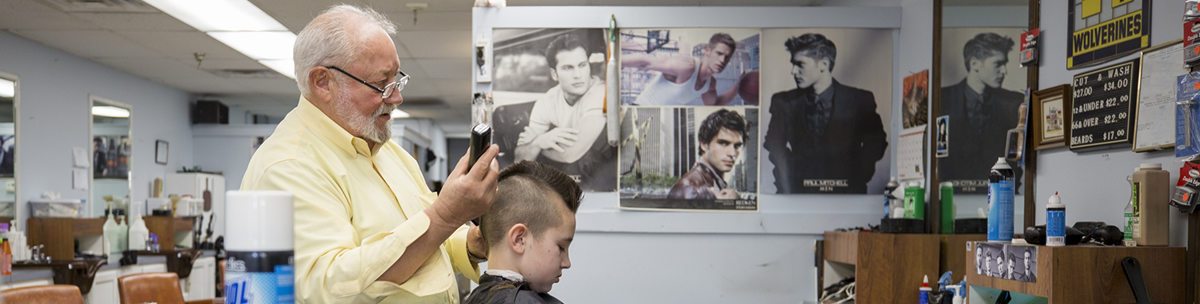 Barber cutting boy's hair in barbershop