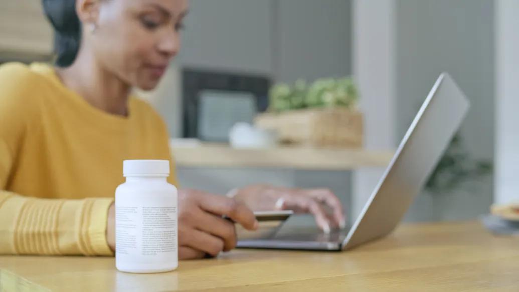 Young woman in front of a computer with a bottle of prescription medications next to her