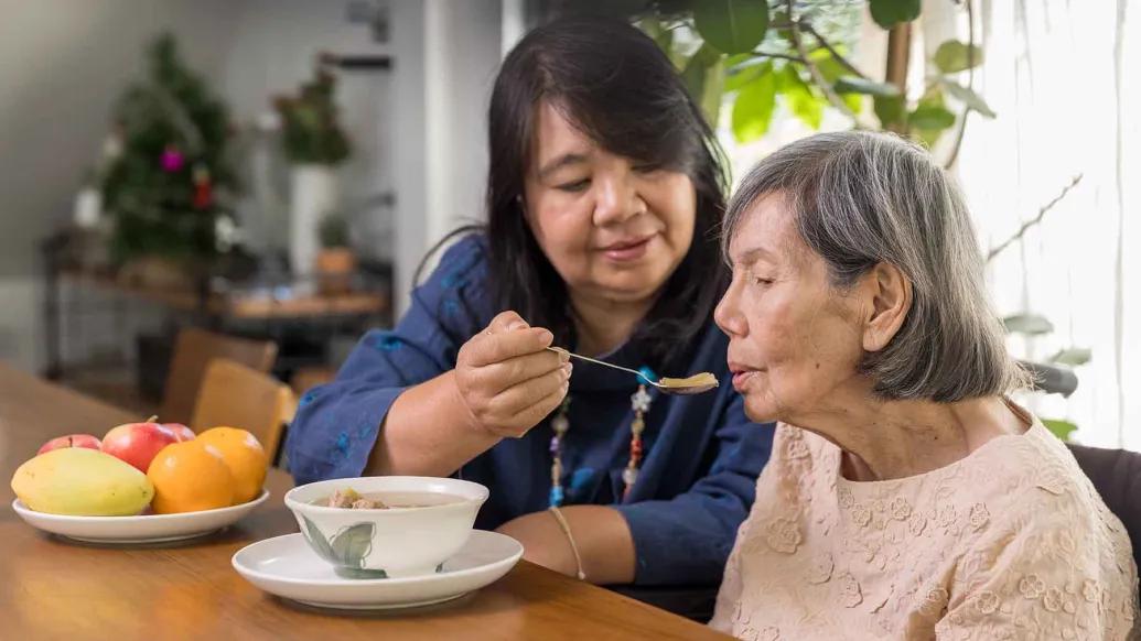 Family caregiver feeding older woman