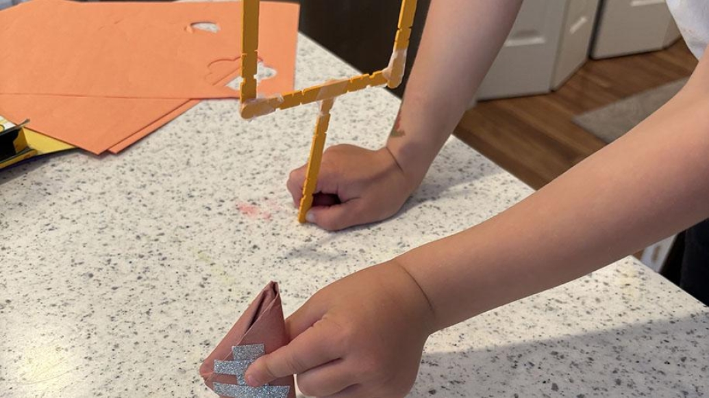 child holds paper football and crafted goalpost