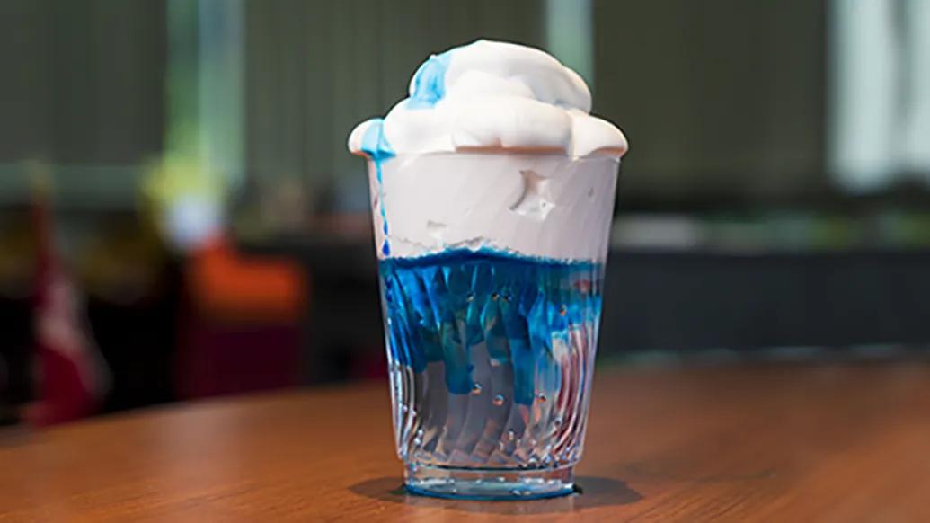 glass filled with white puffy material atop blue liquid