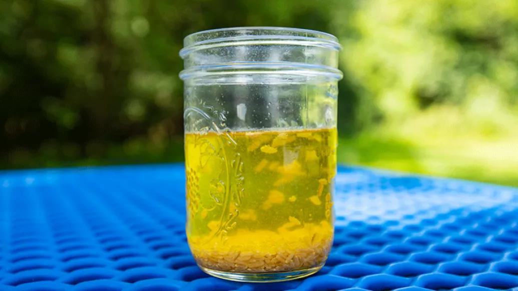 clear jar of yellow liquid with rice floating around