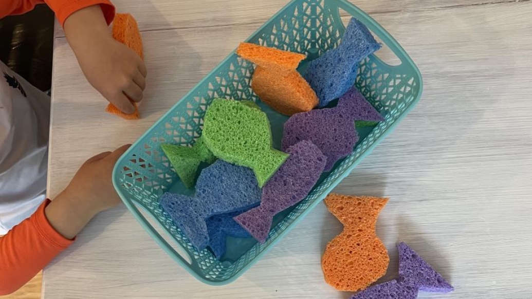 Childing filling up sponge shaped fish in basket