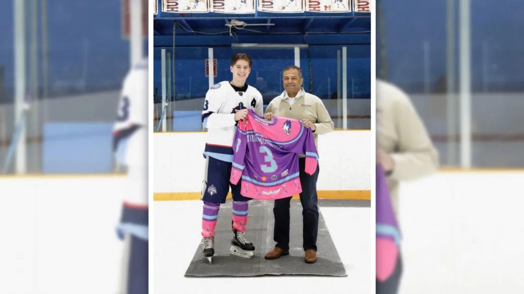 hockey player with doctor on right holding pink and purple jersey
