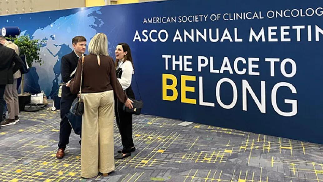 Men and women stand in groups chatting in front of the ASCO 2025 logo sign
