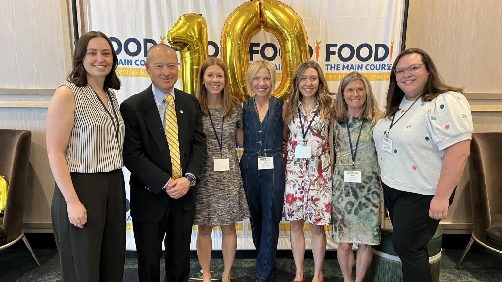 team smiling together in front of 10 year anniversary sign