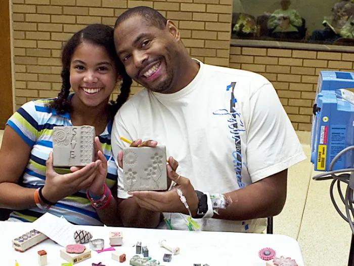 A father and daughter show off their clay artwork