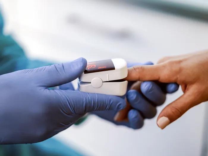 Provider takes a pulse oximetry reading from a patient's finger