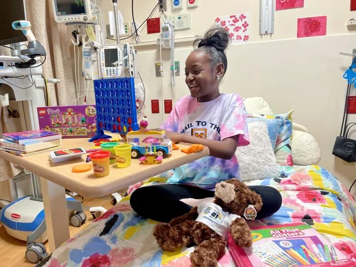 pediatric patient sitting in a hospital bed playing connect four