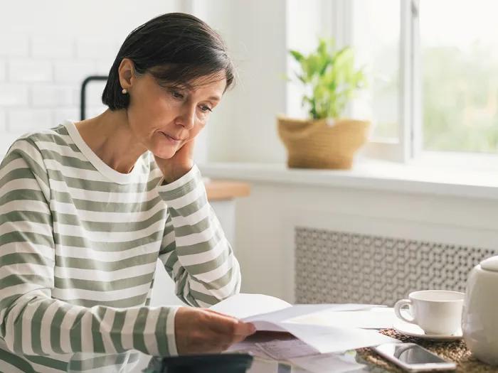woman sitting at table in stripe shirt stressed seeming white background window