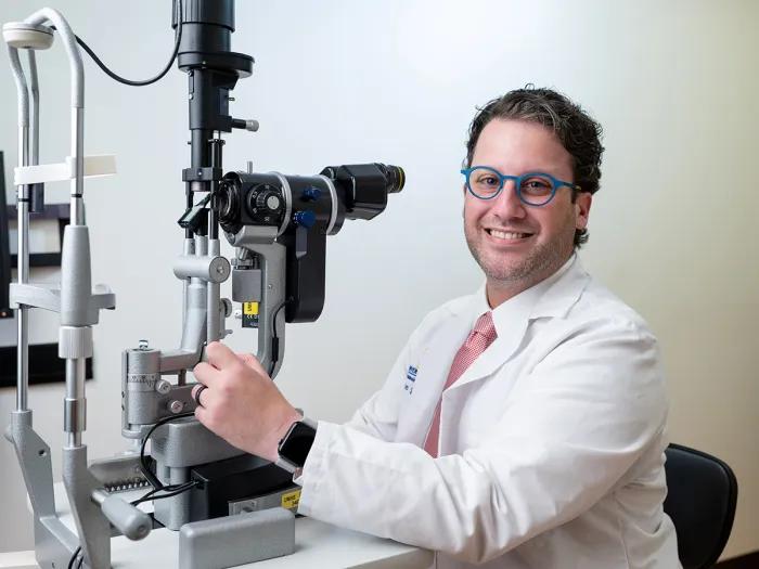 Dr. Adam Jacobsen in front of a slit lamp