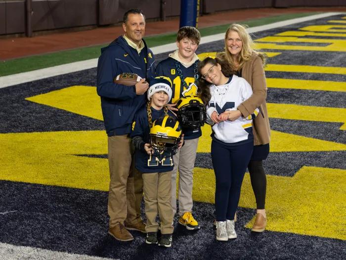 family photo on michigan football field with michigan colors