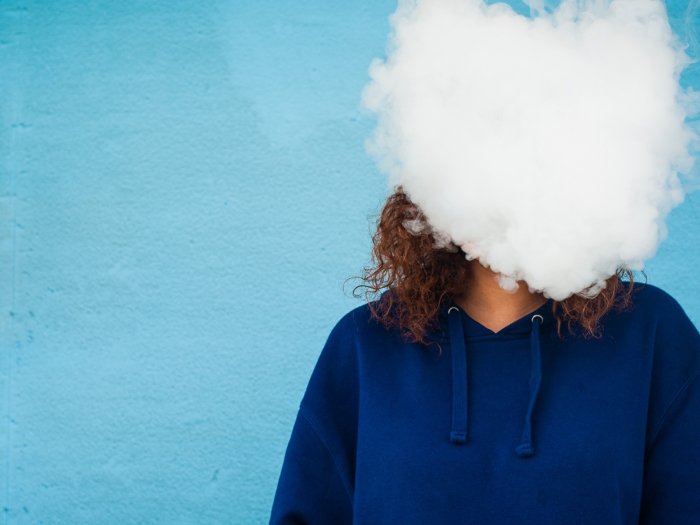 smoke over face of person with blue sweatshirt blue background