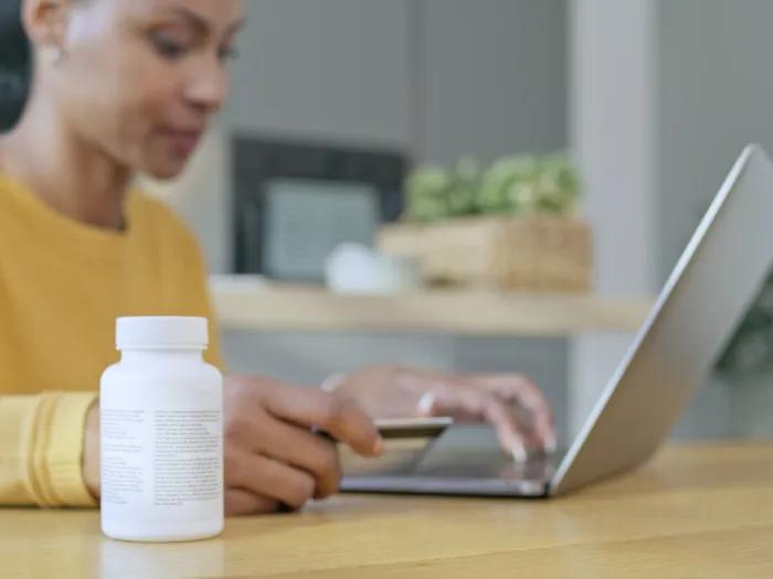 Young woman in front of a computer with a bottle of prescription medications next to her