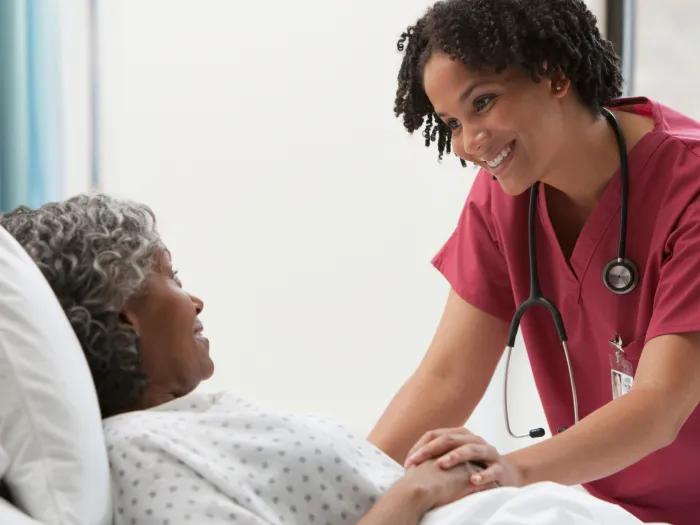nurse in maroon at patient bedside