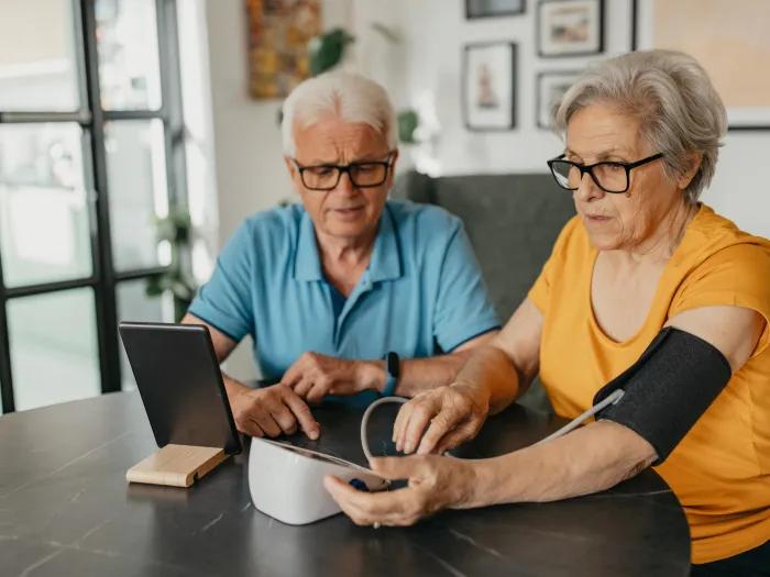 two older people taking blood pressure over breakfast