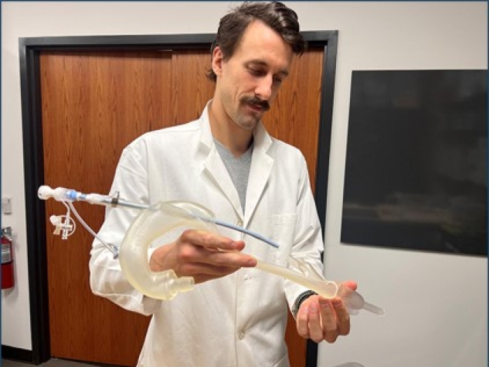 A man is standing in a room while holding a medical device