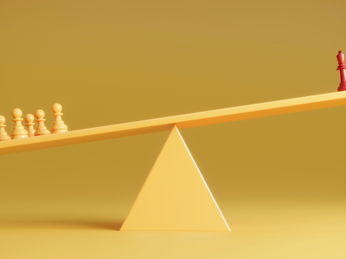 chess pieces yellow background one red piece on right and yellow on left weighing the balance beam down