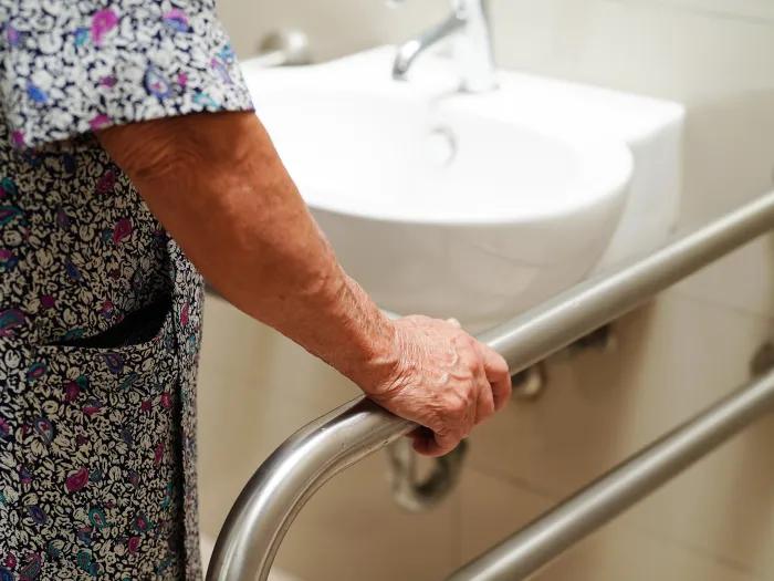 woman holding pole in bathroom with patient gown on