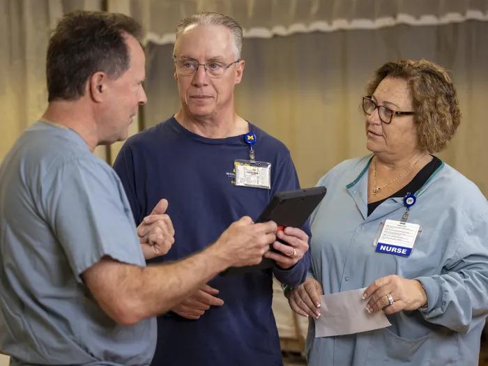 A man talking to two of his care providers in a clinic setting.