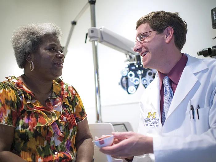 Dr. Grant Comer shows a patient in a colorful blouse a model of the eye