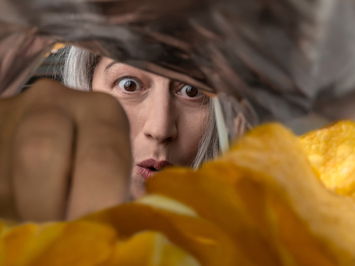 women looking into a chip bag excited you only see her face and hand going into the chips