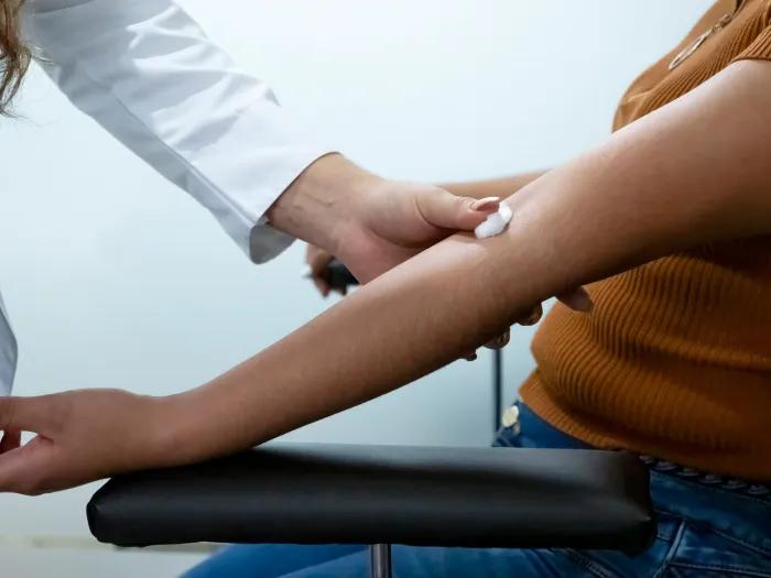 close up of arm out blood being taken from provider in white coat