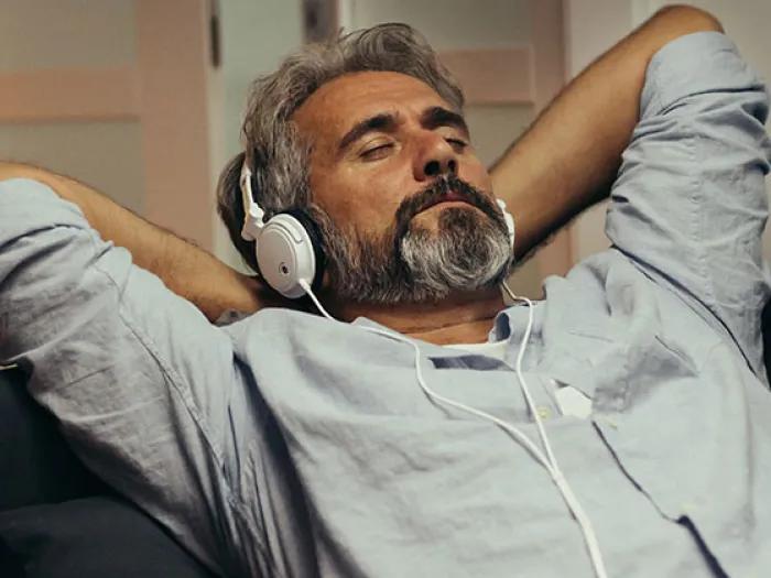 Mature bearded man listens to a podcast while wearing headphones