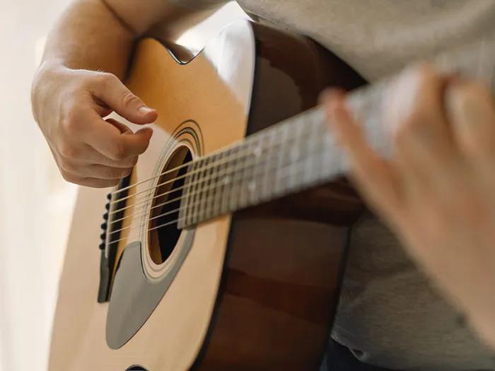 close up of man playing a guitar