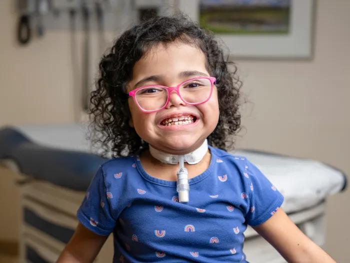 little girl smiling pink glasses in doctor office