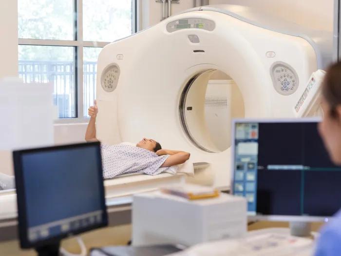 A radiologist talks with a CT scan patient while in the control room.