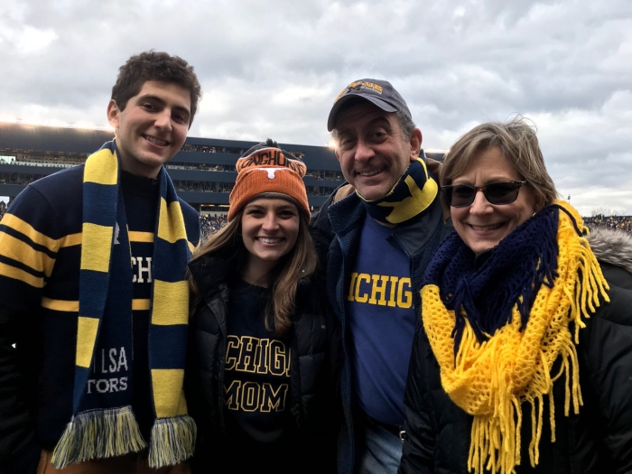 Daniel, Emily, Kenneth, and Kimberly Levin all warmly dressed in U-M gear. They appear to be at a football stadium, and the sky is cloudy.