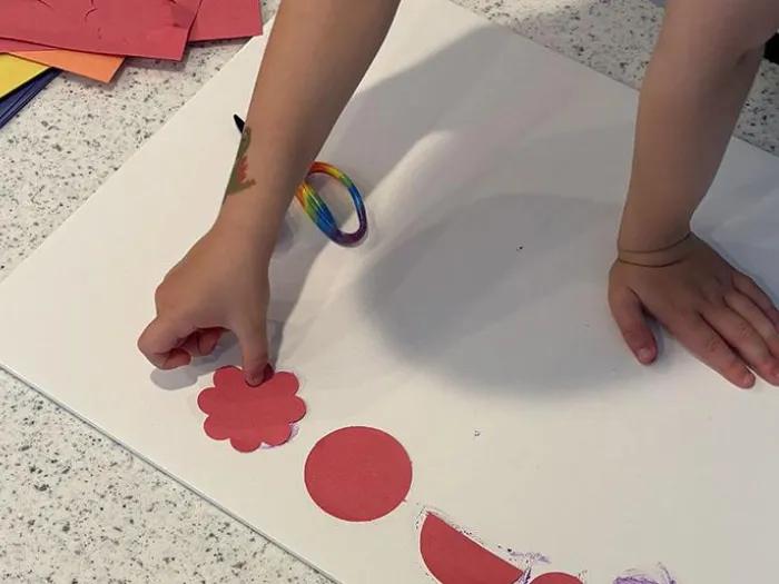 child plays homemade board game with construction paper pieces