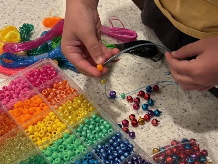 A child is making a colorful friendship bracelets.
