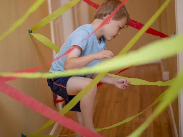 Child zig zagging and taping colored crepe paper to wall