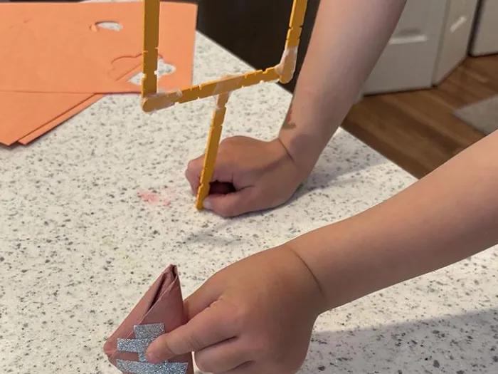 child holds paper football and crafted goalpost