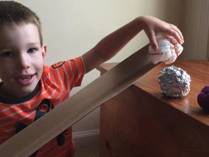 boy plays with ramp and ball experiment
