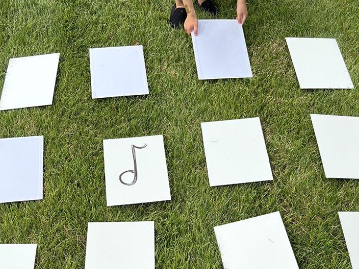 Child placing musical note cards in a row on the grass