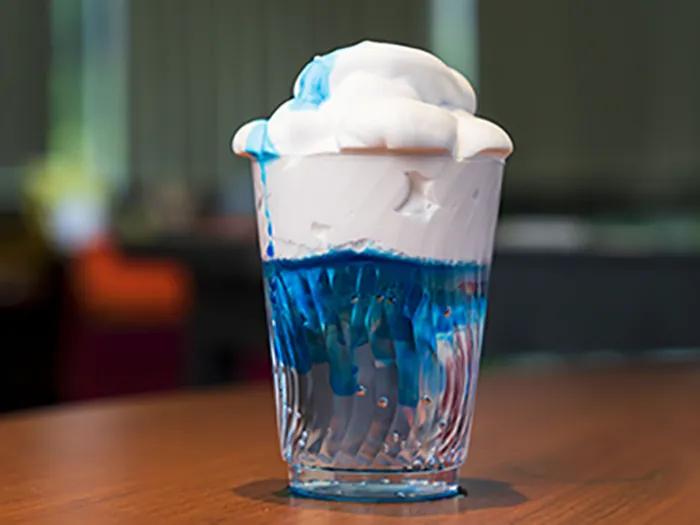 glass filled with white puffy material atop blue liquid