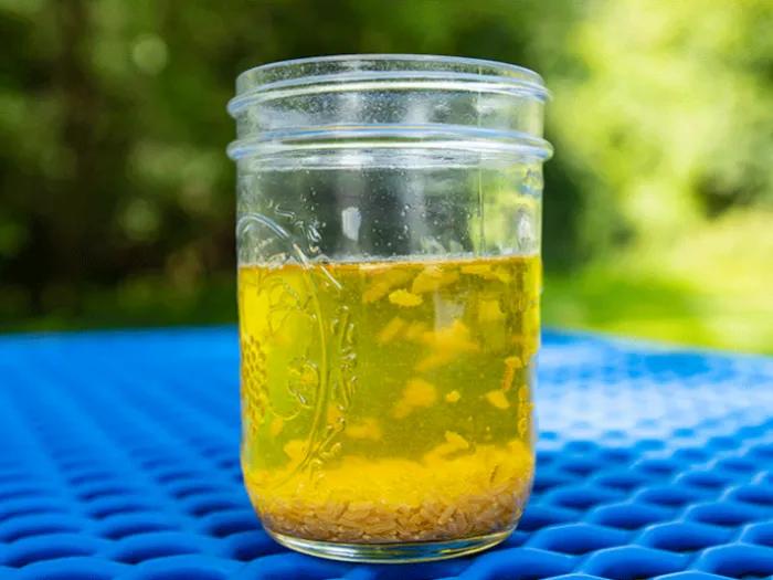 clear jar of yellow liquid with rice floating around