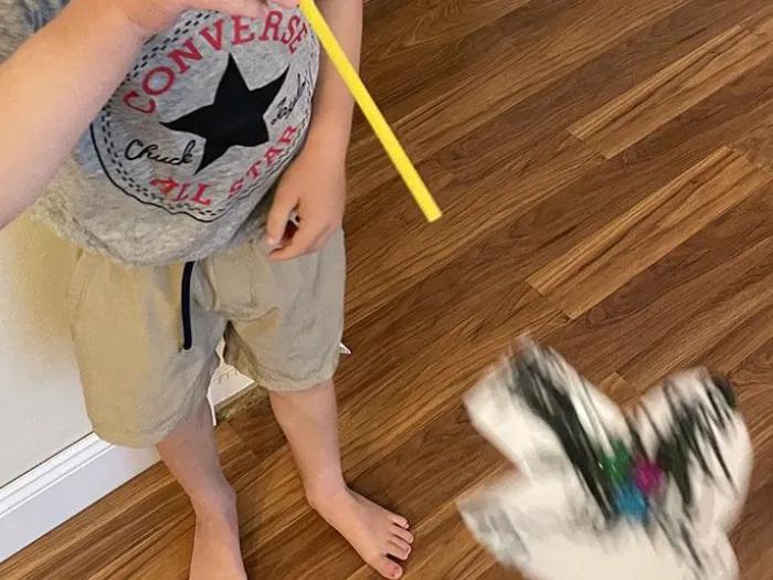 boy blows paper superhero figure off of straw