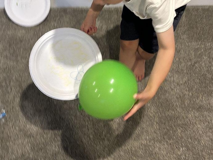 Child scooping green ball onto paper plate