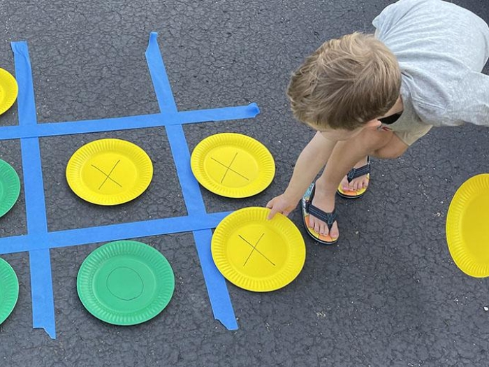 Child placing colored plates within blue tape strips