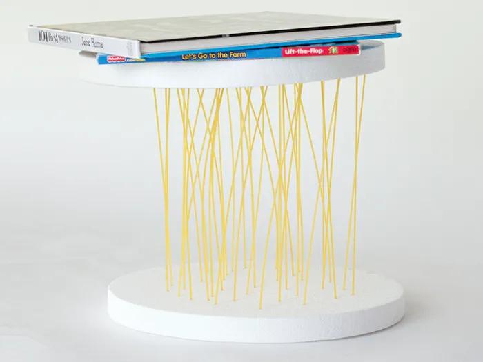 dry spaghetti noodles poked into styrofoam board hold up board and book
