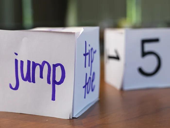 Large dice made out of white paper with numbers and words
