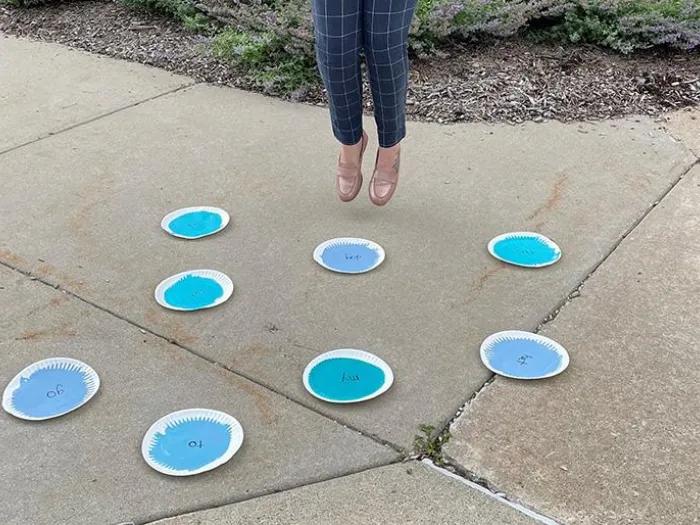 Child jumping over imaginary puddles made of paper and colored blue