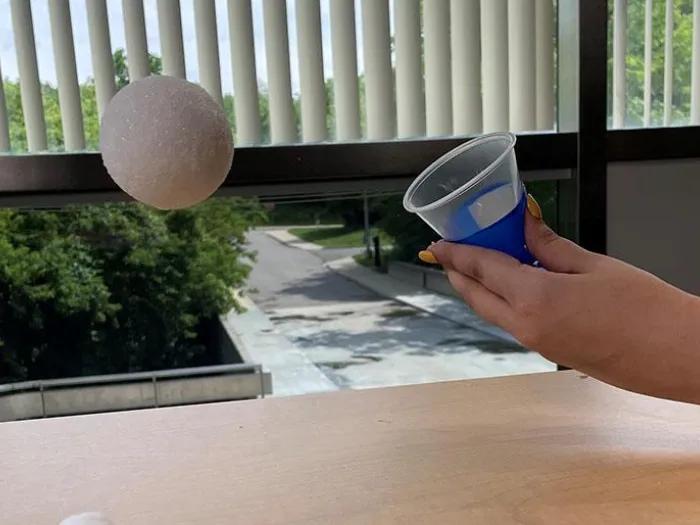 hand squeezes cup, popping snowball into the air