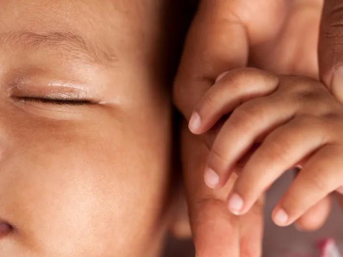baby close up holding parent's hand