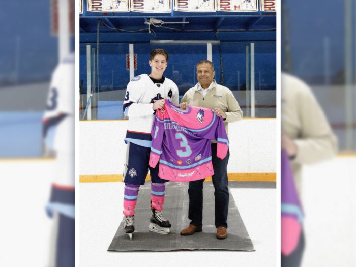 hockey player with doctor on right holding pink and purple jersey