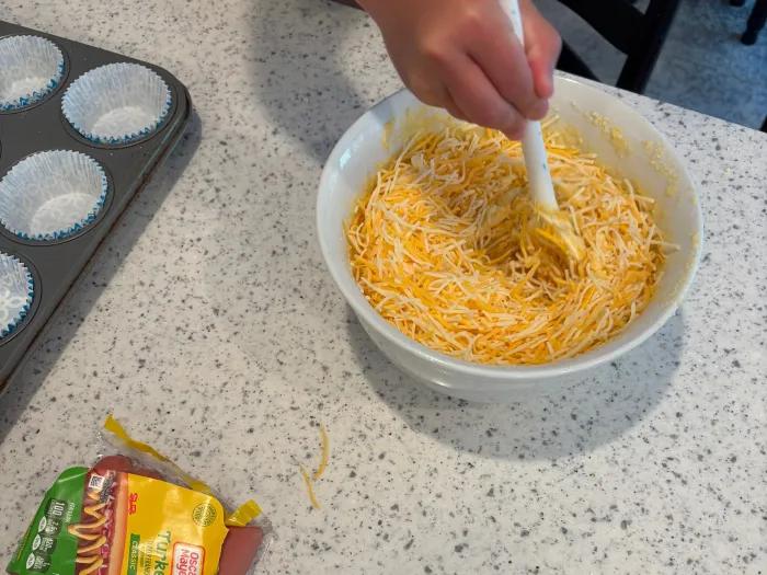 boy stirring cornbread mix with cheese shredded inside